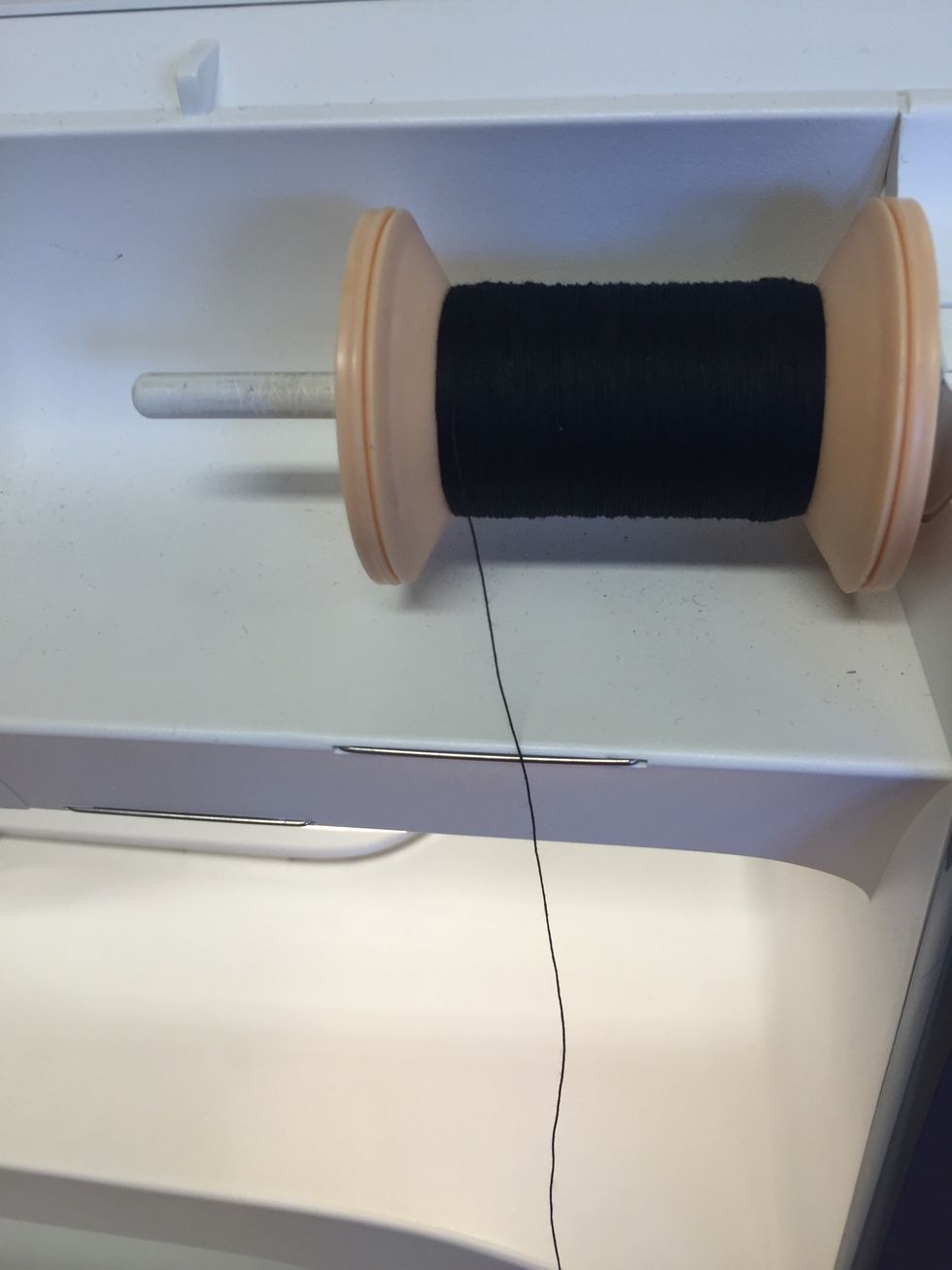 S\u00e4tt dit tr\u00e5drullen. Se till att tr\u00e5den kommer ut mot dig och inte in mot symaskinen.