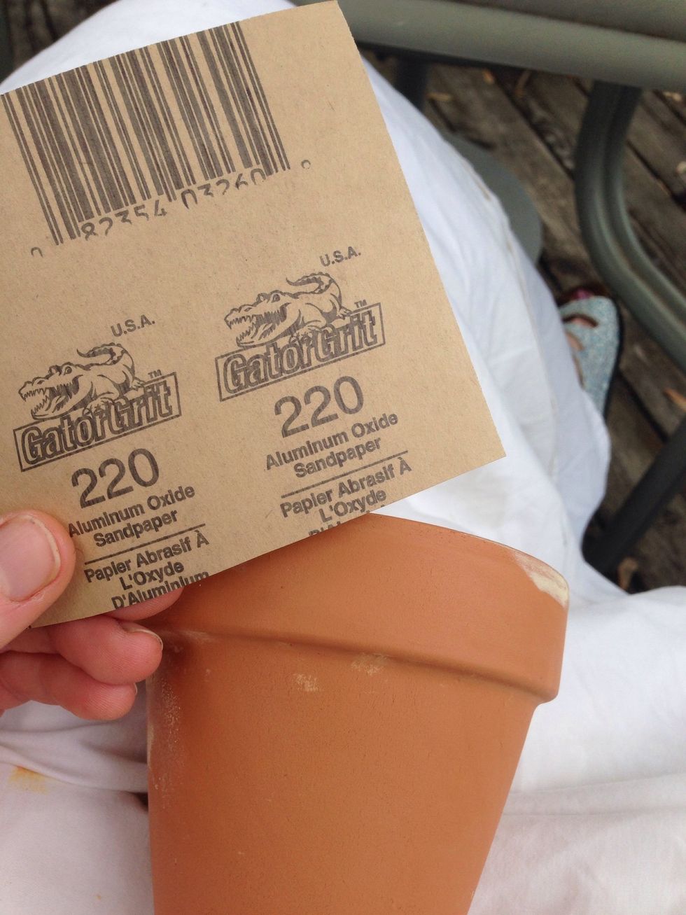 Sand pottery with fine grit sandpaper. You may need a few pieces of paper depending on quantity and size of pots. Pots should feel smooth to the touch.