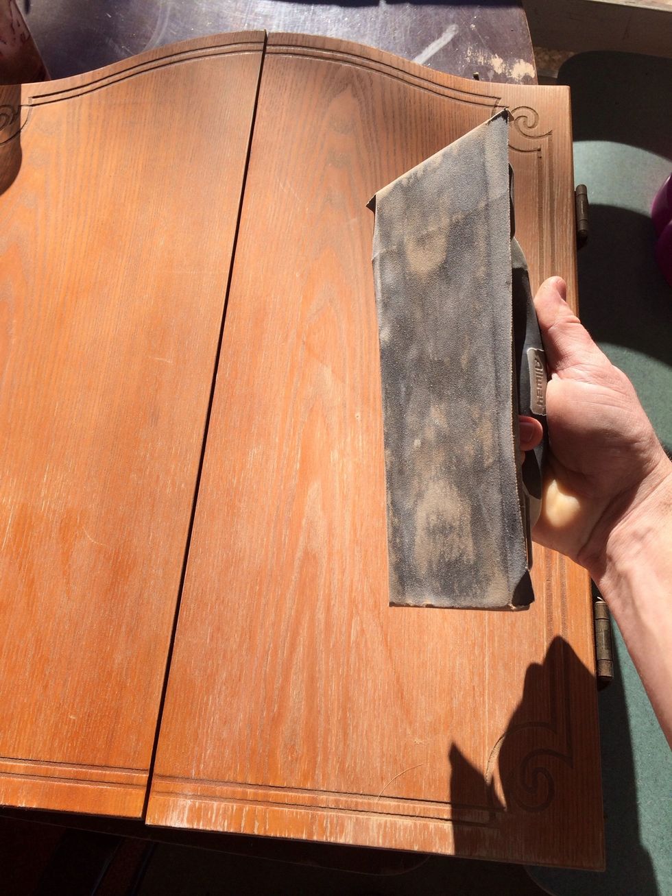 Sand the varnish off. Lightly if it's veneer. I use a manual sander because I'm a Man so I look like I'm doing more work, plus an electric might ruin it. Do this outside unless your into dusty stuff.