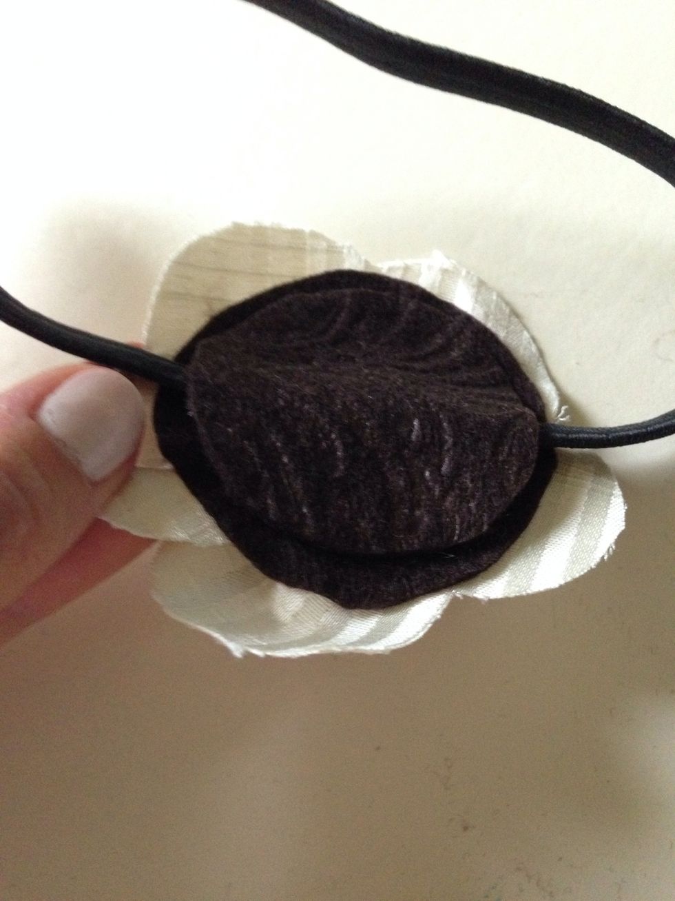 Sandwich the elastic headband between the flower bottom, and the felt circle.