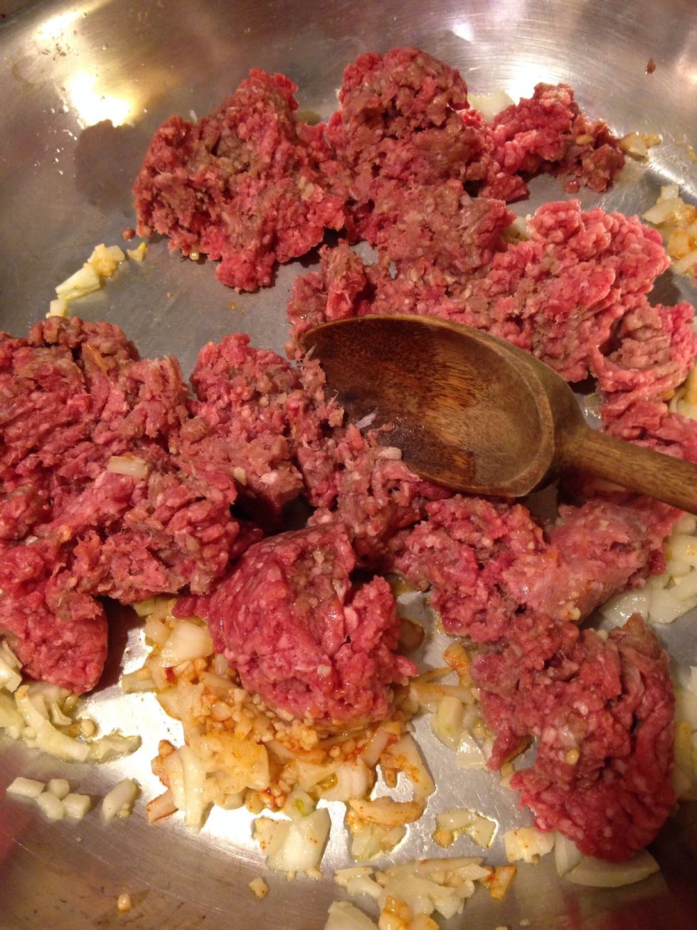 Saut\u00e9 diced onion and minced garlic in a saucepan with garlic and olive oil. When the onions are soft, add the ground beef.