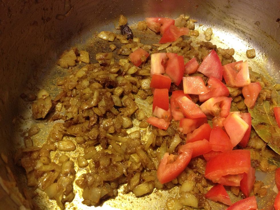 Saut\u00e9 for a few seconds to fry the spices, making them more flavorful. Add in the tomatoes.