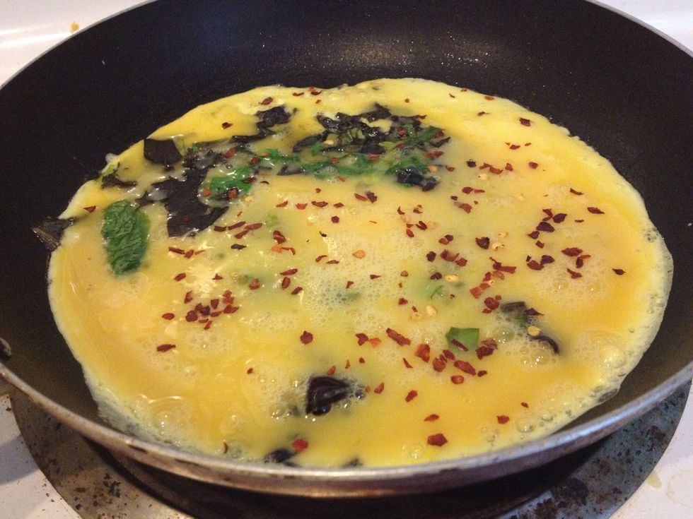 Saut\u00e9e spring mix for 30secs and pour the egg mixture evenly. Cook 2mins on med heat until firm watching the corners. (optional): sprinkle a few chilli flakes for the contrast.