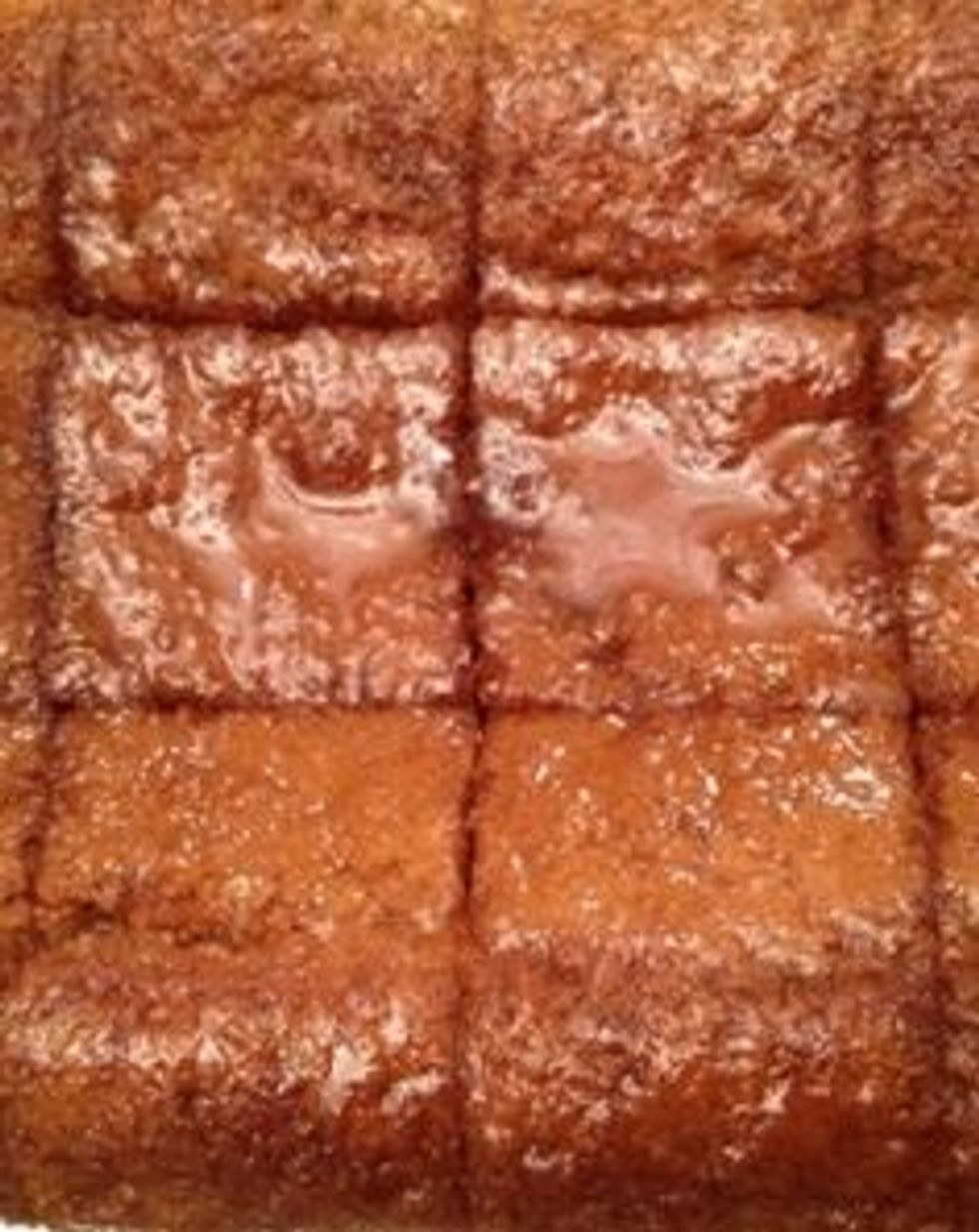 Scar the cake into pieces, and slowly ladle the hot syrup over the cold cake, allowing time for each ladle of syrup to be absorbed.