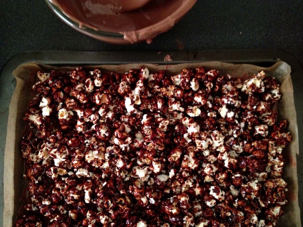Scatter popcorn evenly across the chocolate in the tray. Break large pieces if necessary and ensure popcorn is as separate as possible. Very, very gently pat the popcorn into the chocolate.