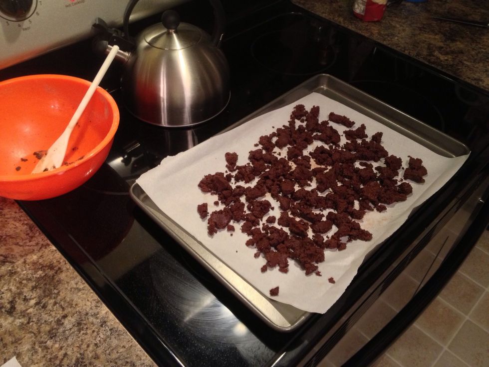 Scatter the chocolate crumb clusters across the parchment paper evenly.