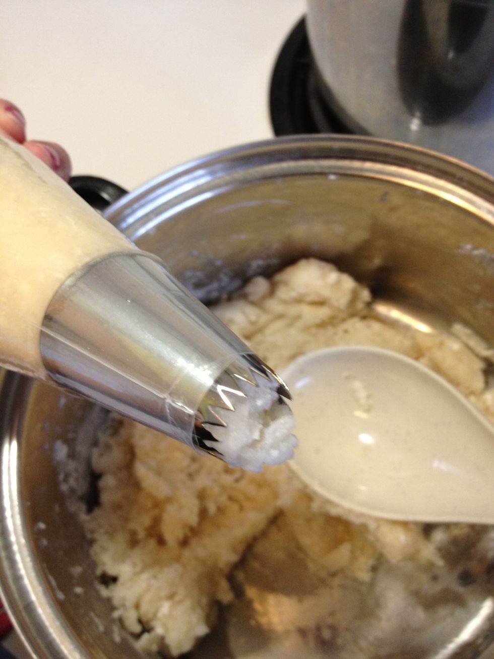 Scoop a little bit of dough into your piping bag (1/3 full). Small amounts at a time will be much easier to pipe. Be careful! The dough is still warm/hot! You can let it cool for a bit if you prefer.