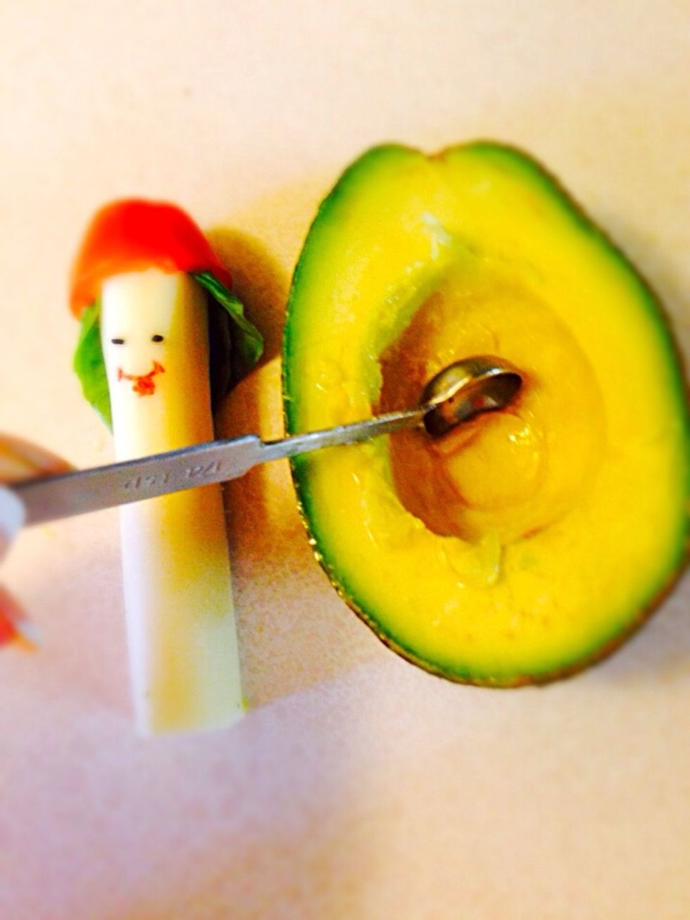 Scoop avocado with measuring spoon just enough to fit in cheese stick