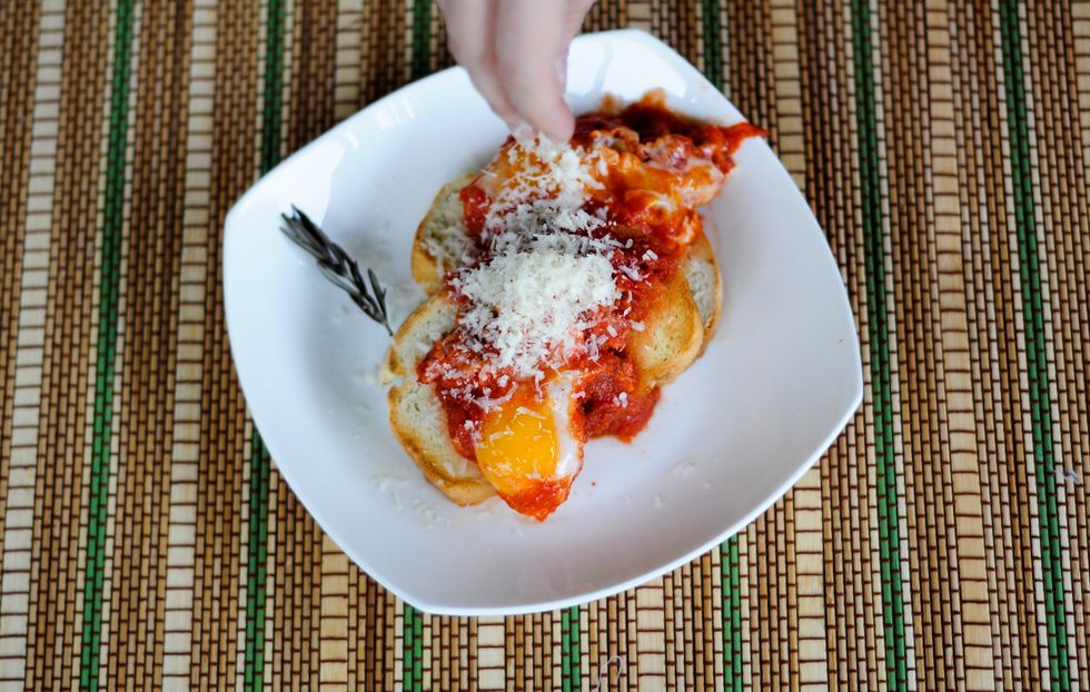 Scoop eggs and tomato sauce over thickly-sliced, toasted bread. Top with cheese, and season with salt and pepper, if desired. Serve hot.