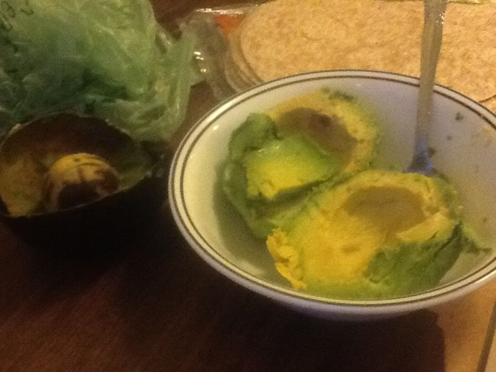 Scoop out avacado from peel and mash it with a fork