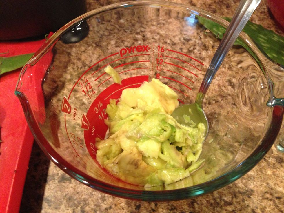 Scoop out one half of the avocado and mash.