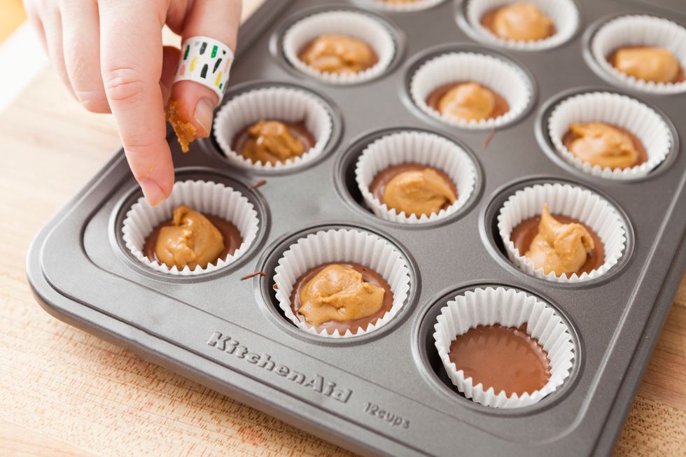 Scoop up one teaspoon of the peanut butter filling and roll into a ball. Then flatten it slightly and place in the center of the muffin cup. Repeat with all peanut butter cups.