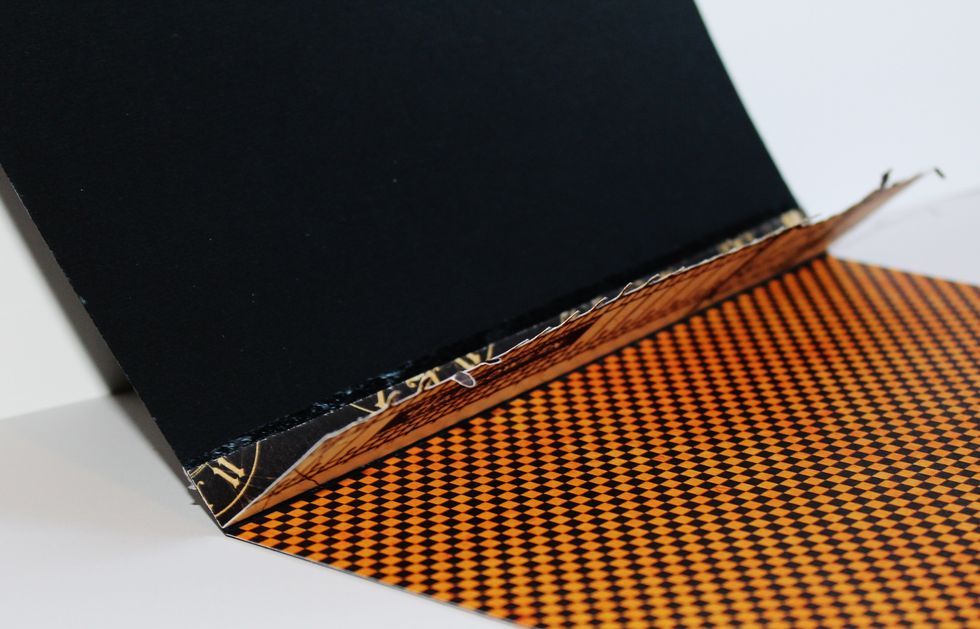 Score 8" x 12" black card stock in half to form card. Adhere pattern paper to inside of card. Fussy cut fence from pattern paper; leaving 1" at bottom of fence when cutting out.