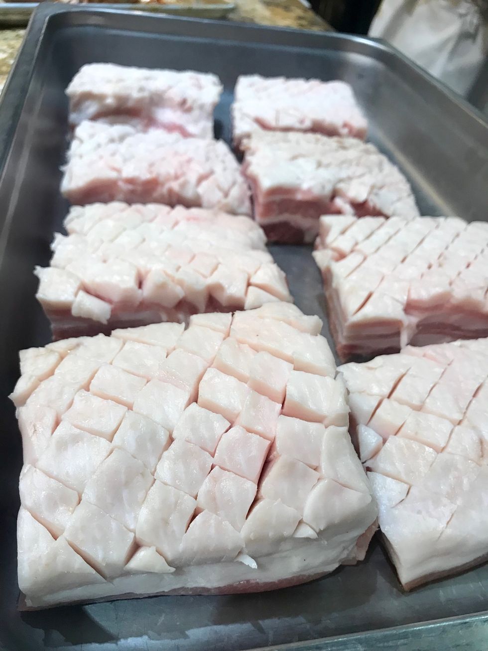 Score pork belly pieces and place fat side up in a hotel pan.
