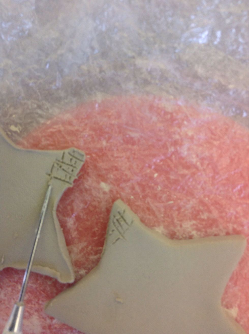 Scratch both surfaces where shapes will overlap, in a cross cross manner. Rub water on both surfaces