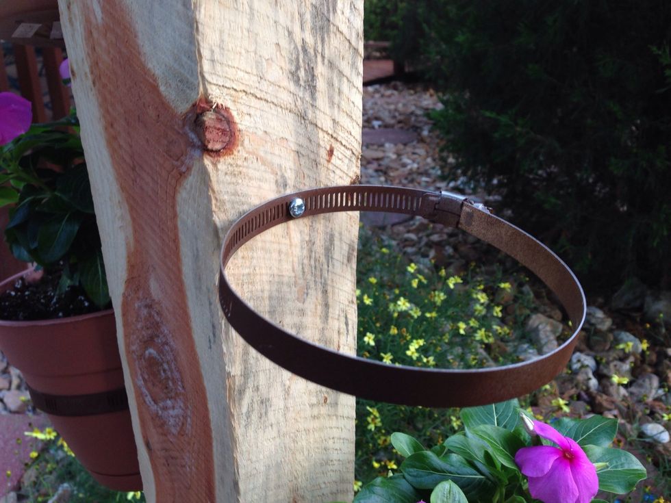 Screw the band clamps into the post where you want the flower pots placed. I painted these clamps brown. I had to drill a hole in each clamp for the screw to go through.