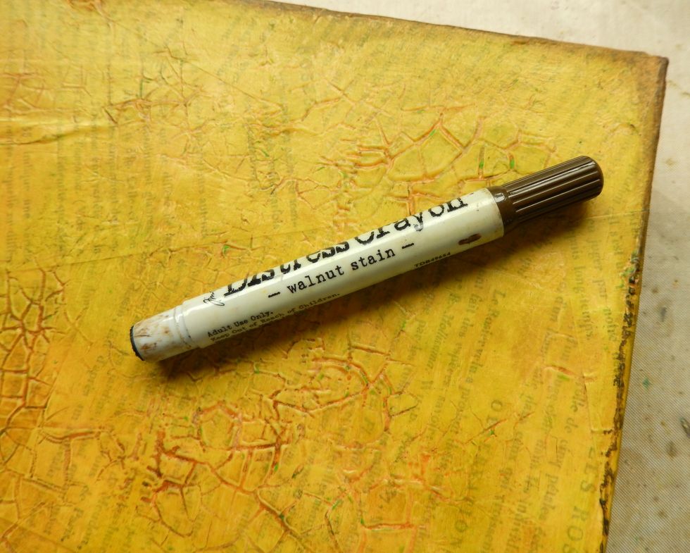 Scribble Walnut Stain Distress Crayon along the edges of your canvas and into the 'crackled' areas, blending with your finger or a dry sponge.