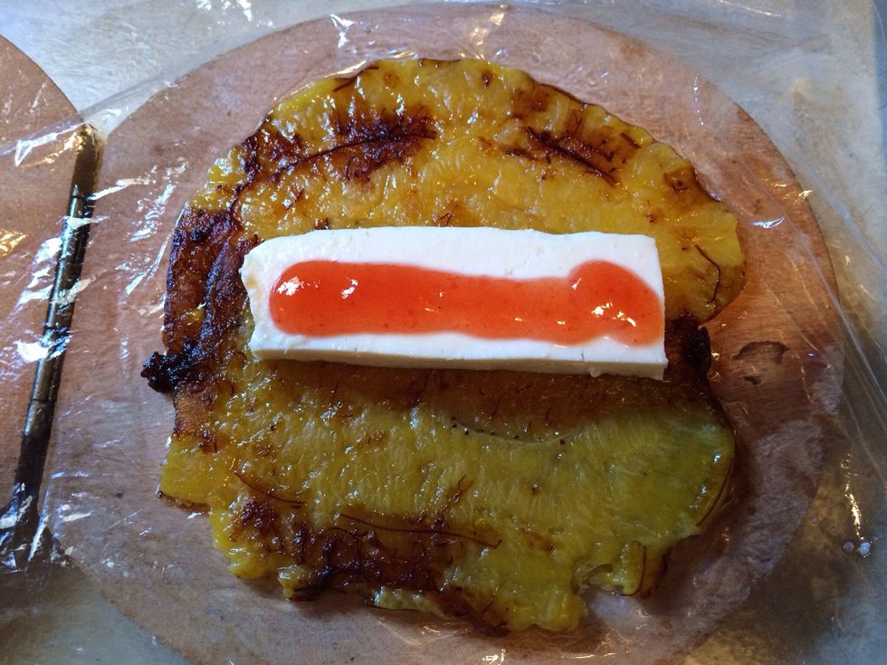 Se pone sobre el pl\u00e1tano una tajada gruesa de queso y mermelada de guayaba
