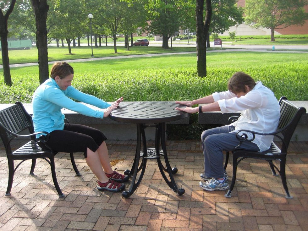 Seated cat-palms on table, arms extended. Round back and let head curl in toward stomach