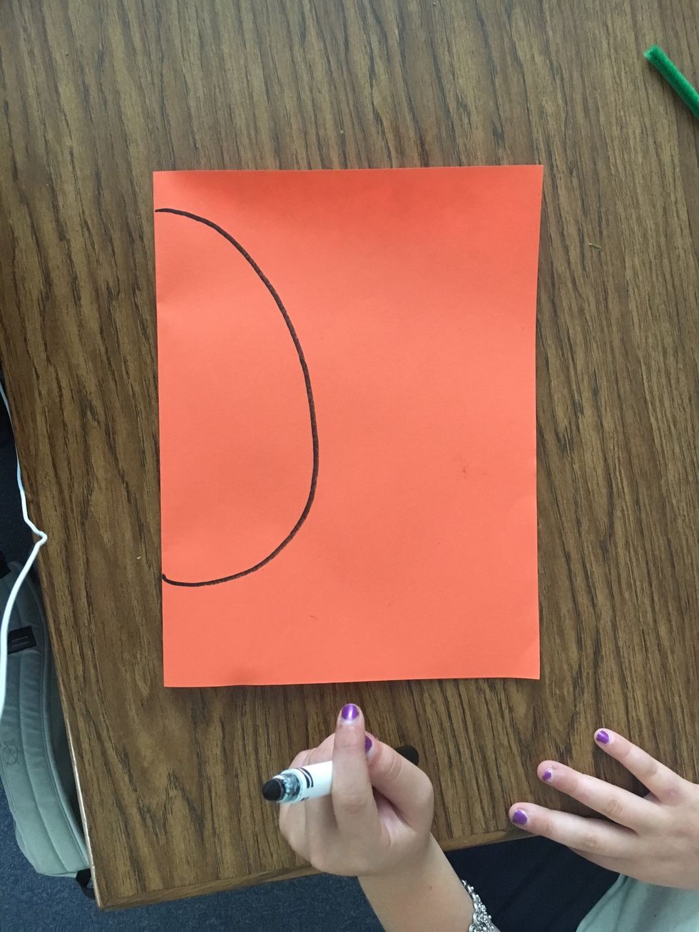Second, draw a large backwards "C" on the folded side of the orange construction paper.