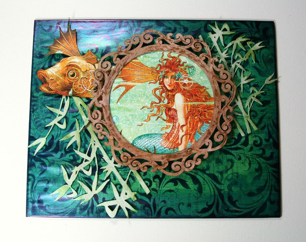 Secure mermaid image from G45 Voyage Beneath the Sea to prepared Flourish Frame and attach to panel with adhesive foam spacers.