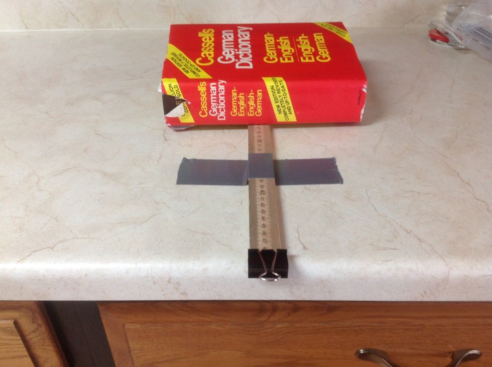 Secure the half meter stick with one piece of duct tape and place a heavy book toward the back of the half meter stick. This prevents the stick from sliding from side to side.