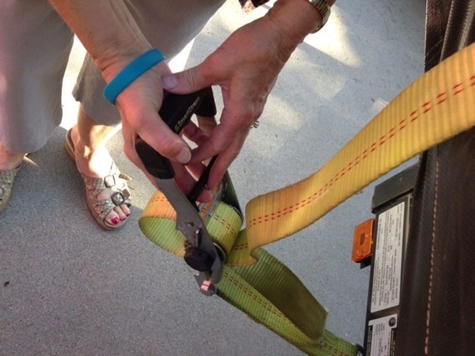 Securely ratchet the yellow cargo strap over the cover, hooked under the left and right side of the trailer frame, fitting over the support bar across the front of the float.