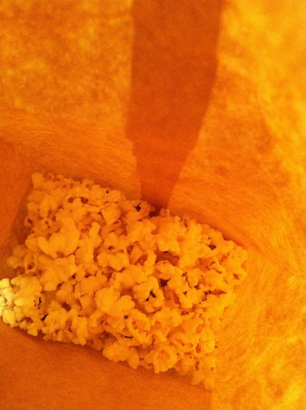 See, all popped and delicious smelling. To be honest, plain popcorn is very bland. This next step should happen quickly, while the popcorn is still hot. Pour your oil and spice mix right into the bag.