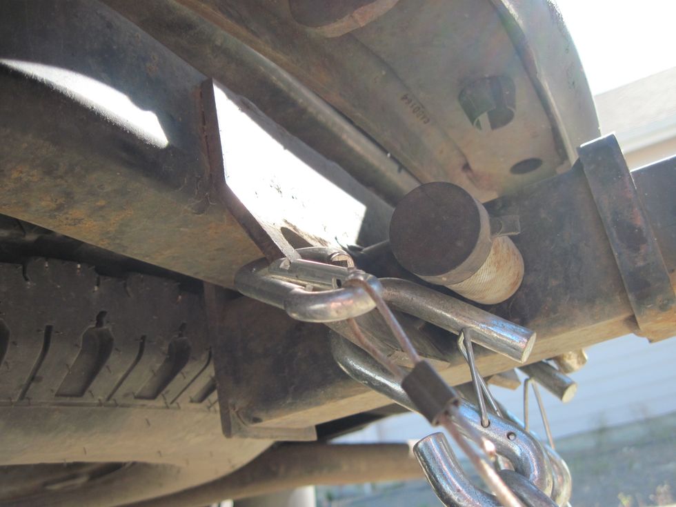 See the carabiner hook on the wire is hooked to the steel tab where the chain is also hooked. This little wire is in case the trailer breaks away, the brakes will come on automatically.
