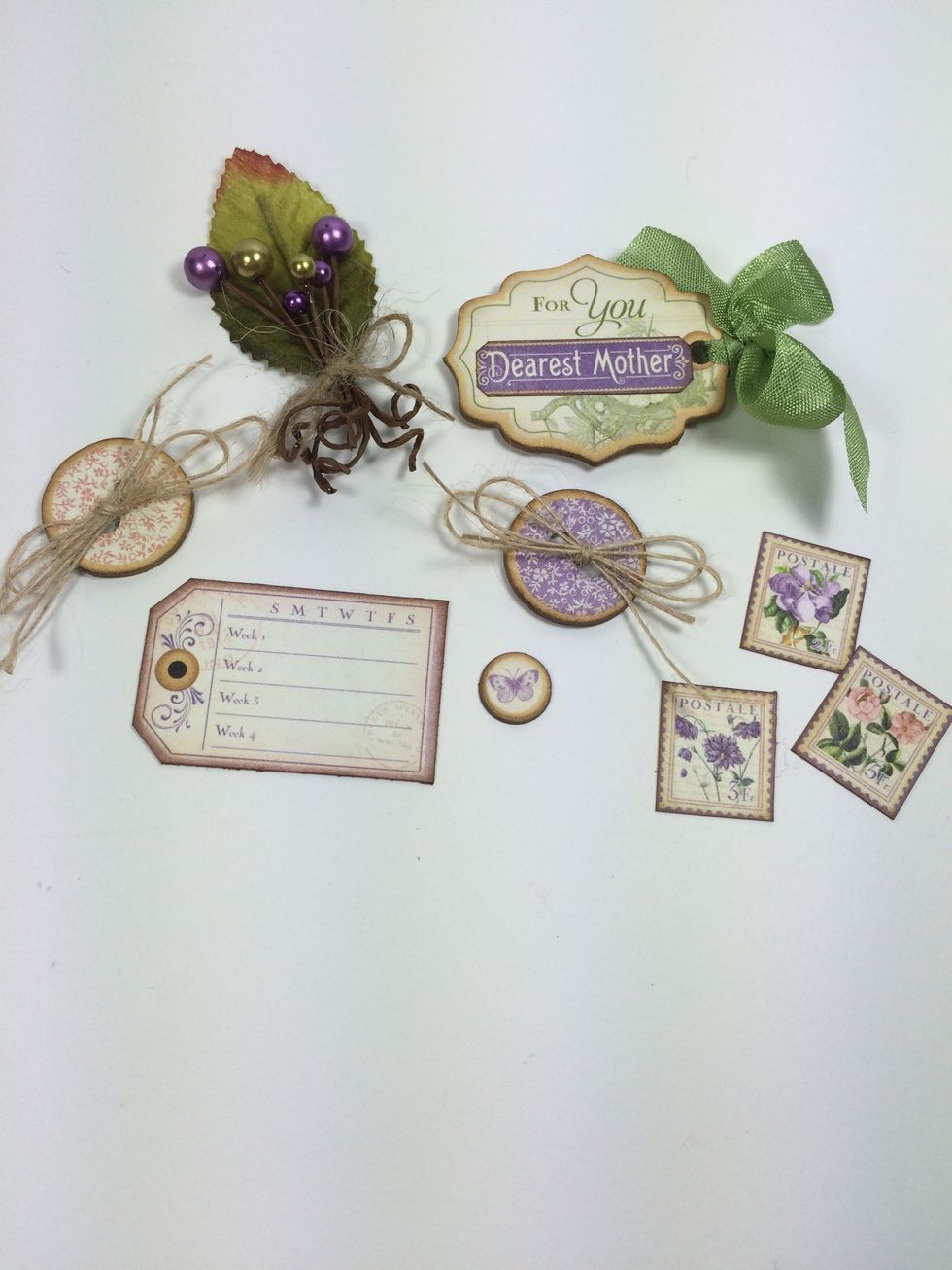 Select some chipboard pieces, cut-aparts and flower stem. I used Petaloo Spring Berry Clusters. I added thin natural twine to the chipboard buttons and May Arts Olive wrinkled ribbon for the tag.