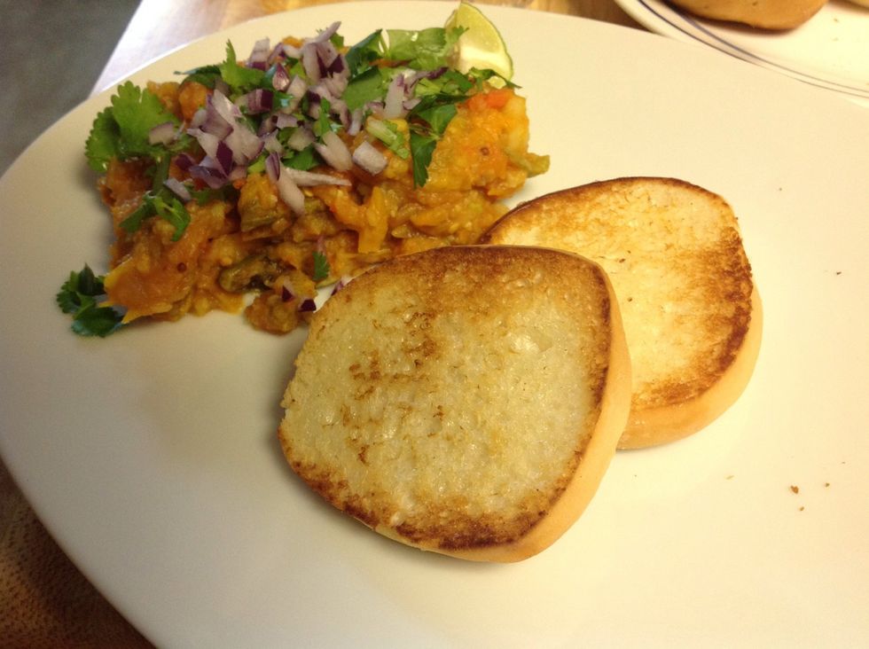 Serve hot with butter toasted bread/bun (Pav). Sprinkle some chopped raw onions and cilantro on the vegetable mixture (Bhaji). Enjoy!!