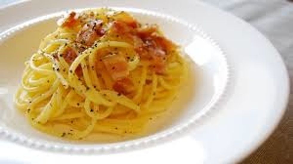 serving the spaghetti alla carbonara with a sprinkling of black pepper