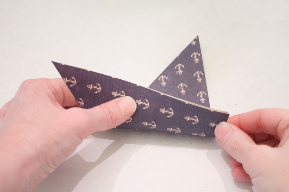 Set in front of you with one of the long sides facing you and the tip in upper right corner. Fold up from the bottom as shown- you make it a little off kilter so the rear corner hangs out a bit