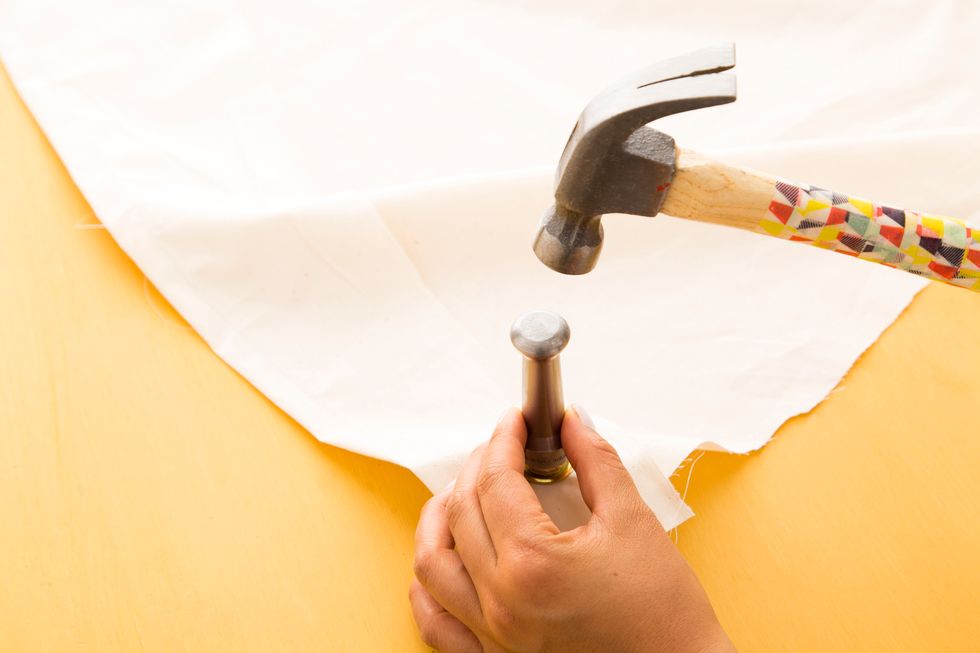 Set the second part of your grommet tool on top and hammer hard so that your grommet is locked and secured. Repeat on all four corners.