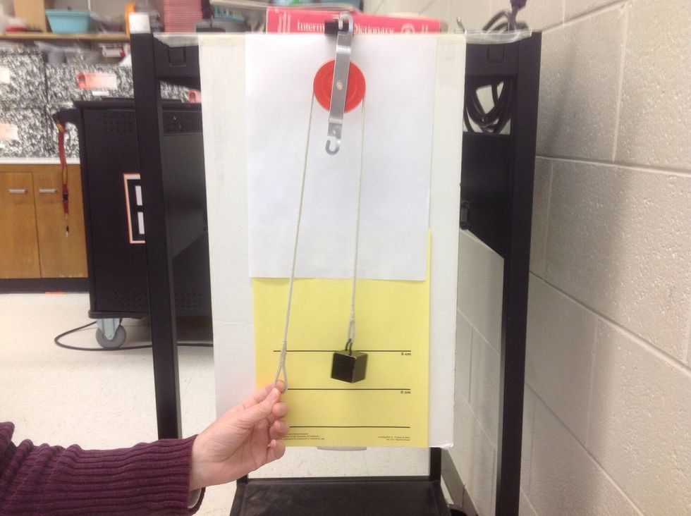 Set up a single pulley system.  Hang the fixed pulley for the upper loop of the binder clip.  Use a single load.  You do not need a spring scale.