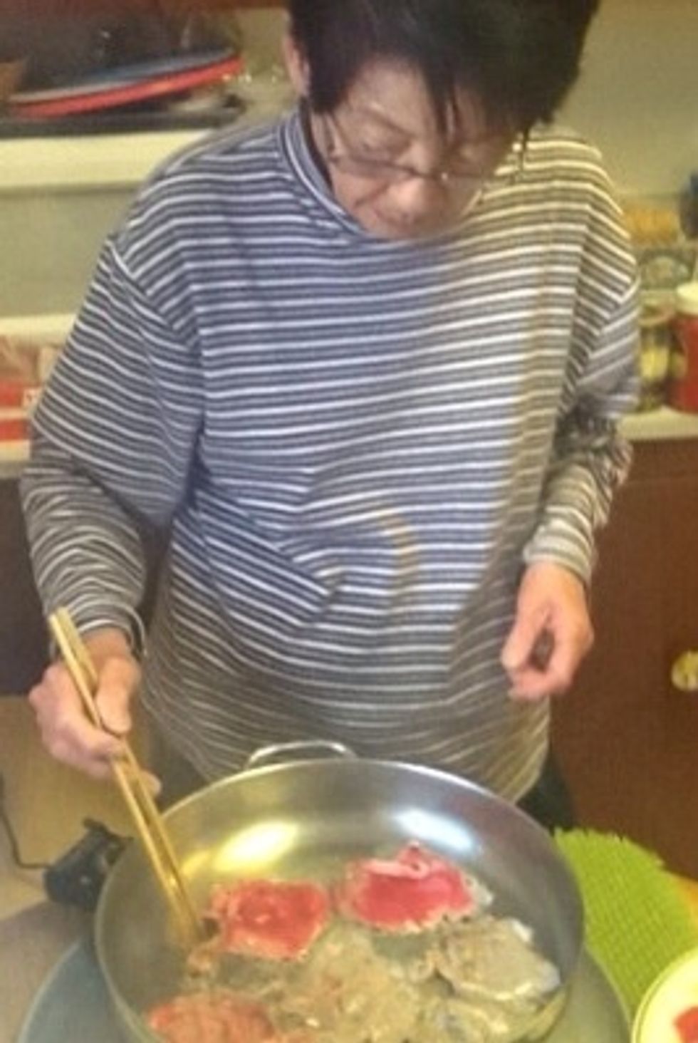 Setsuko sets the electric skillet at medium and puts in a dollop of vegetable oil. She doesn't measure anything.