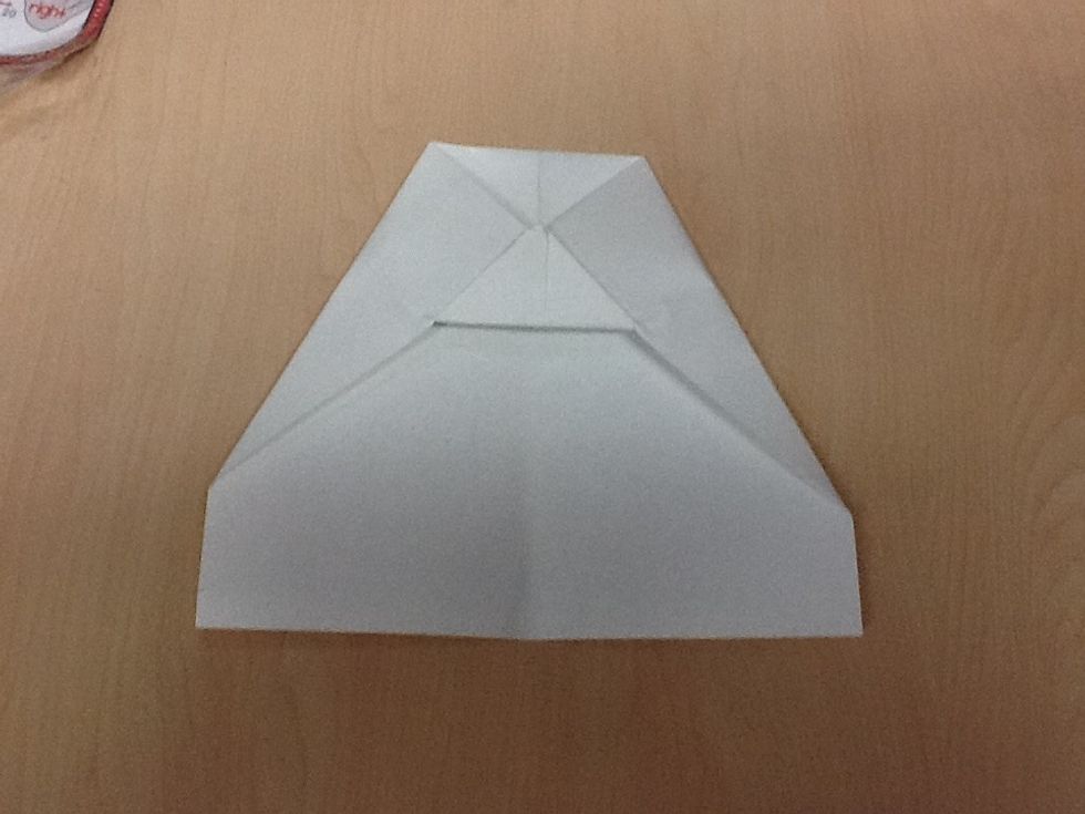 Seventh, fold the tip of the top corner over the side corners.