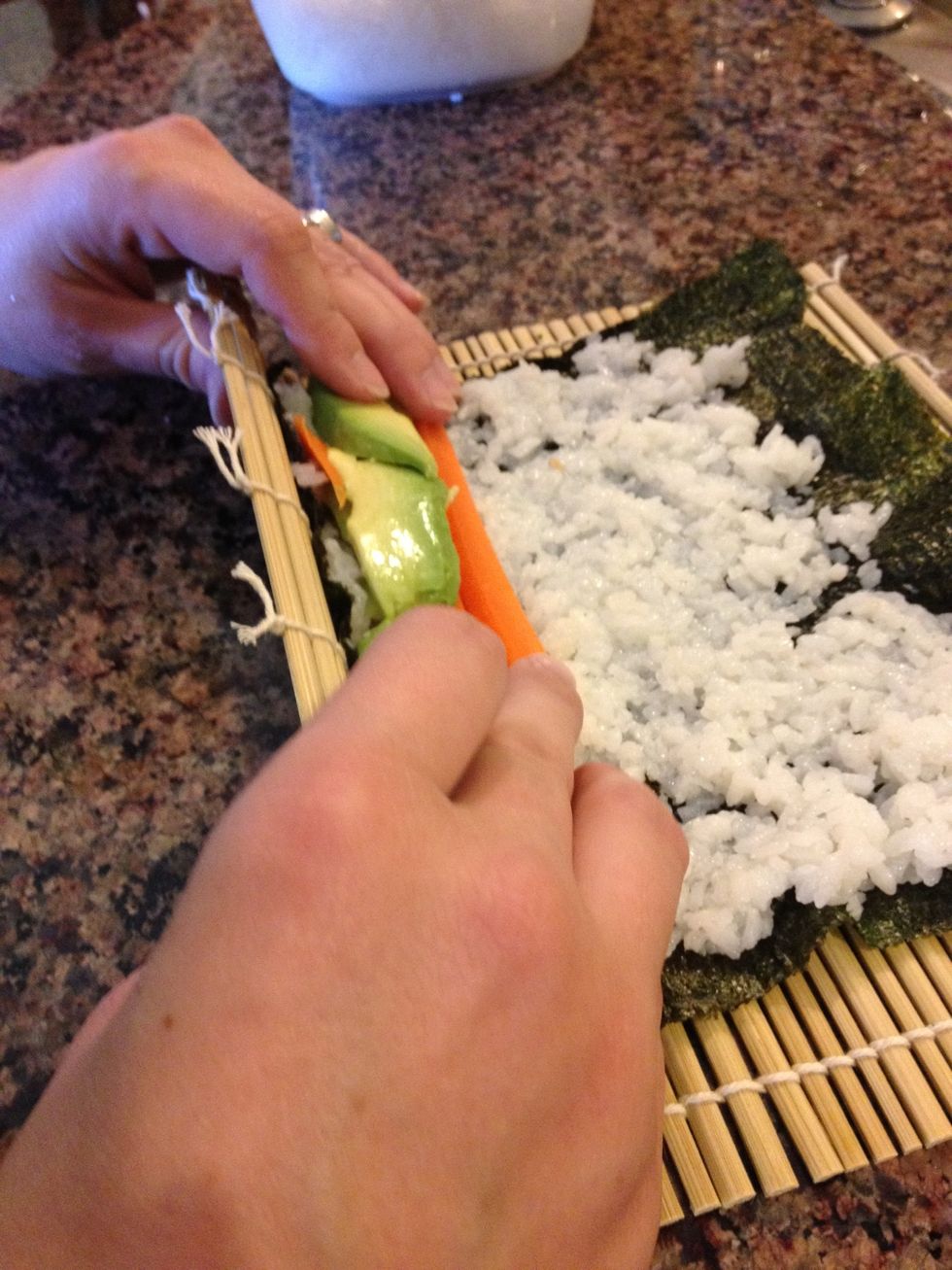 Show kids to roll the nori over using the bamboo mat...