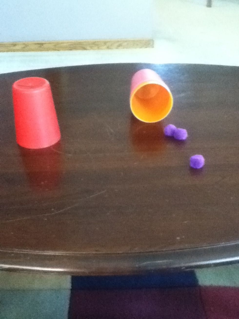 Show the inside of the cup to the audience and point at the puff balls
