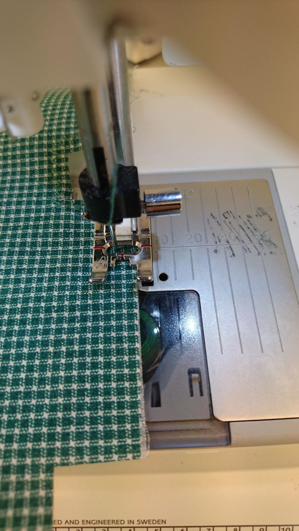 Sicksacka kanterna runt tyget och vlieselinet. Ena t\u00e5n p\u00e5 pressarfoten ska g\u00e5r utanf\u00f6r kanten p\u00e5 tyget.