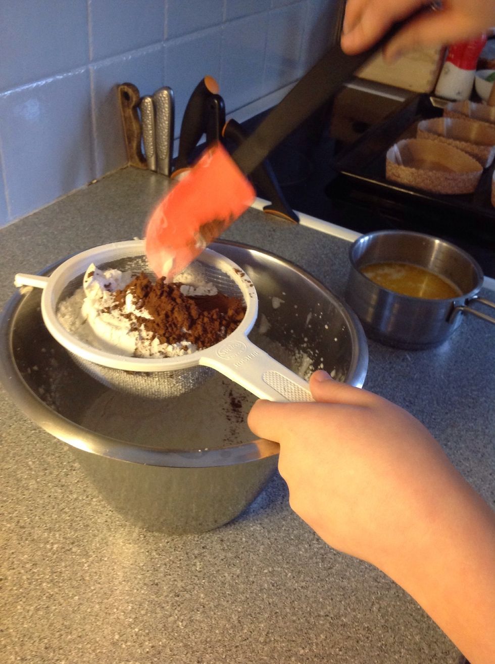 Sikta ner mj\u00f6let, bakpulvret, vaniljsockret och kakaon i smeten, Sift down the flour, baking powder, vanilla sugar and the cocoa in the mixture