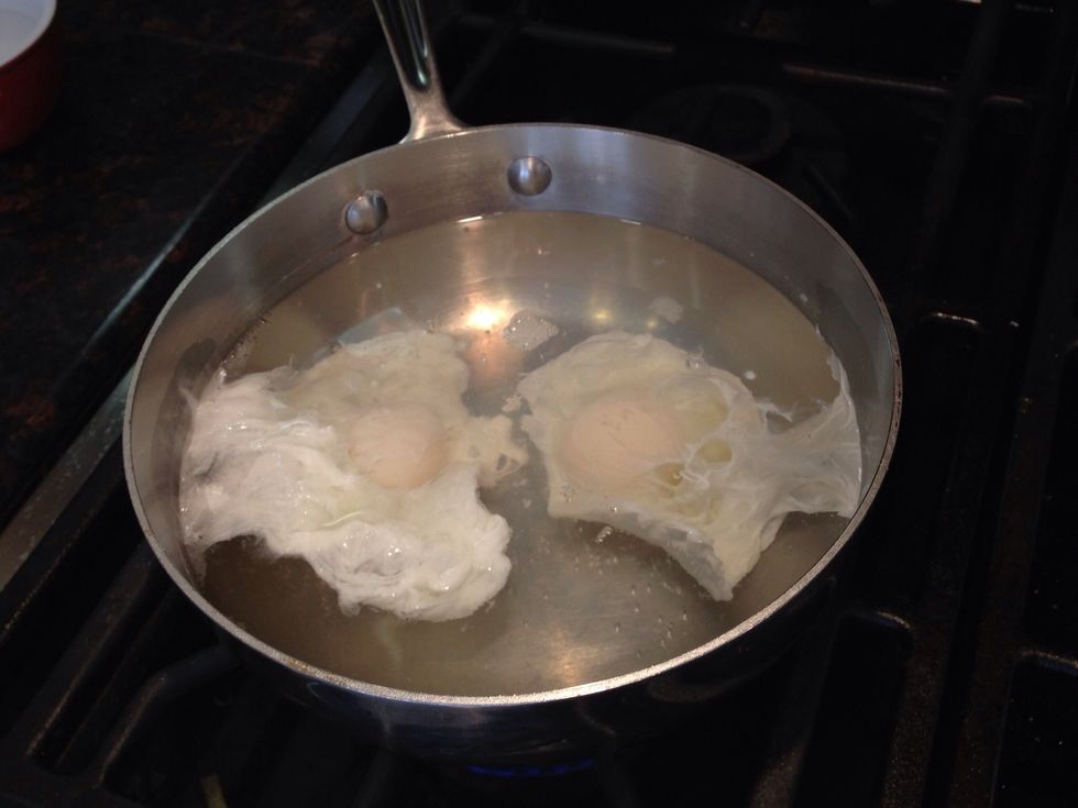 Simmer water and add a touch of salt. Crack one egg per bowl and pour each egg down the side of the water to keep its shape. Cook eggs at a slow simmer for 5 minutes and then remove from flame.