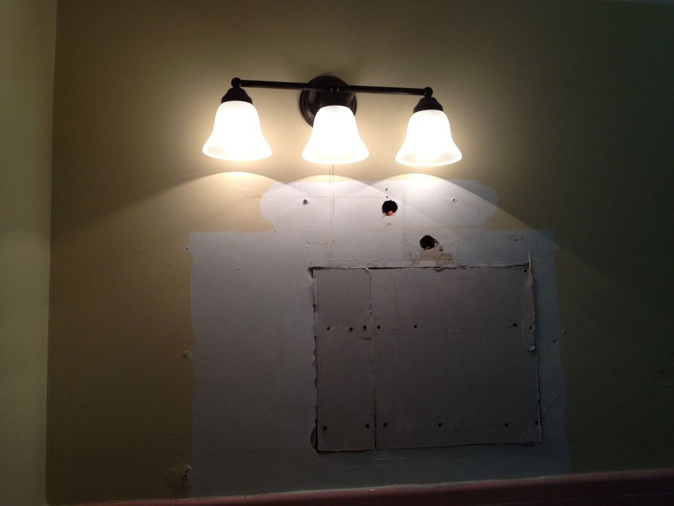 Since the gap was uneven, I had to chip away at parts of the sheet rock with a saw to make it lay flat.  After that I drilled a hole to run the wires for the light above the center for the new mirror.