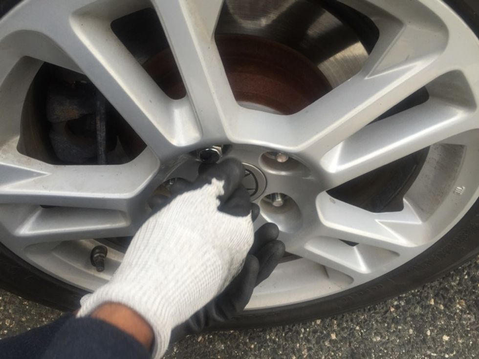 Since you previously loosened the lug nuts with the lug nut wrench, you can now use your hands to fully remove them.