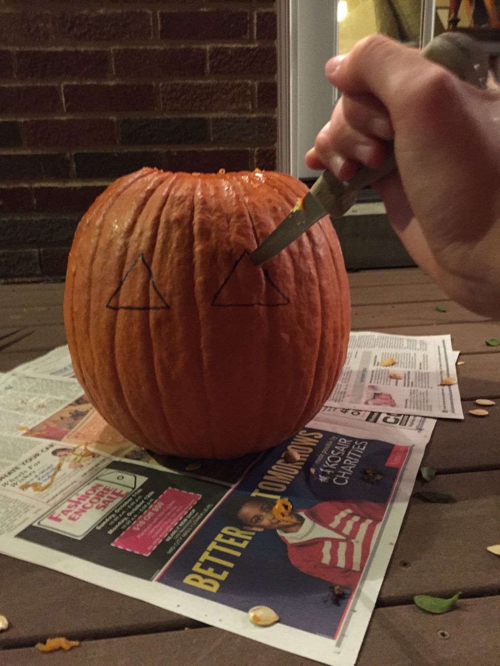 Sketch the eyes onto the pumpkin in whatever shape you choose. Carefully cut out the eyes with your knife along the lines of your sketch. Pop the eyes out after you completely cut all the way around.