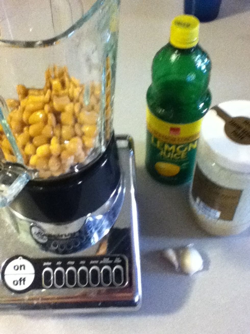 Skin yer garlic and add that to the blender, then drizzle some tahini in there, then pour some lemon juice in last. Start small (maybe a quarter cup of each?), you can add more of anything later.