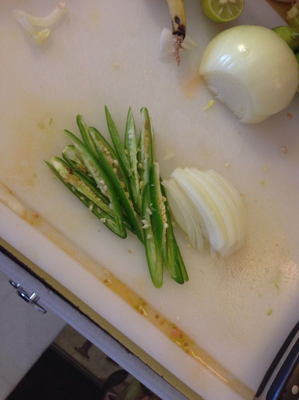 Slice 2 Serrano peppers and 1/4 of an onion. Also add about a finger's width of oil to your frying pan and start warming the oil up as you begin to roll your taquitos.