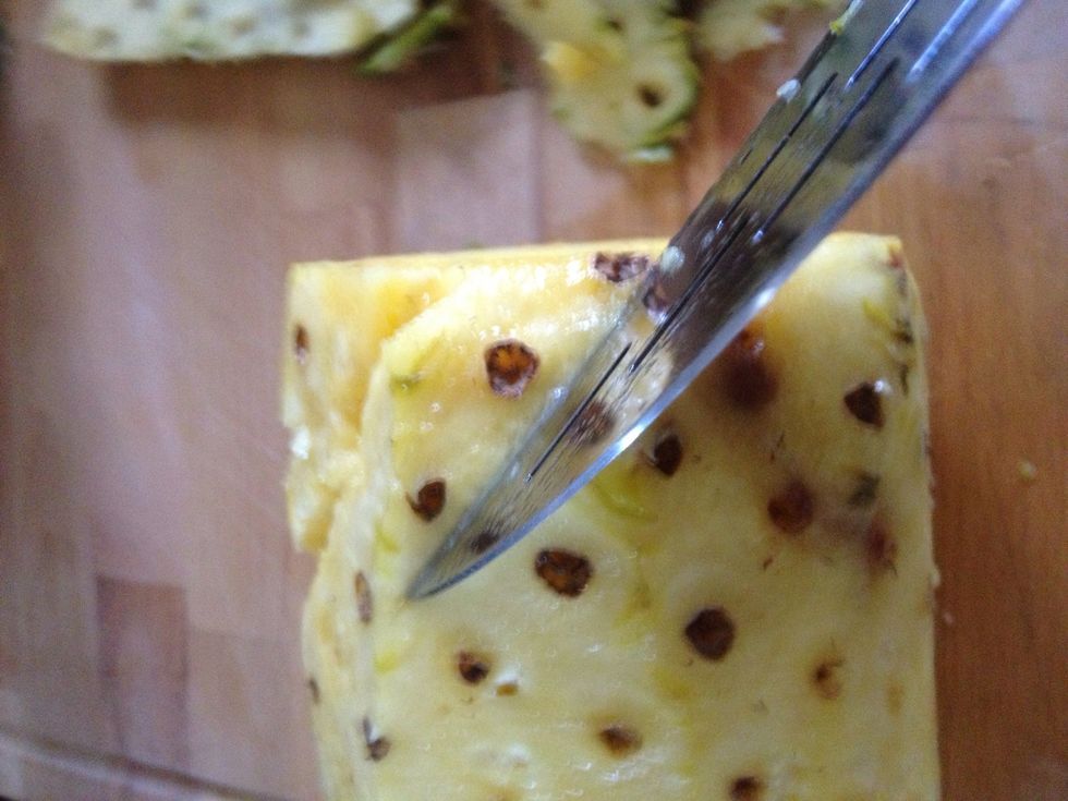 Slice at a 45\u2022 angle. Do not slice deeply into the pineapple, but just deep enough to remove the eyes.