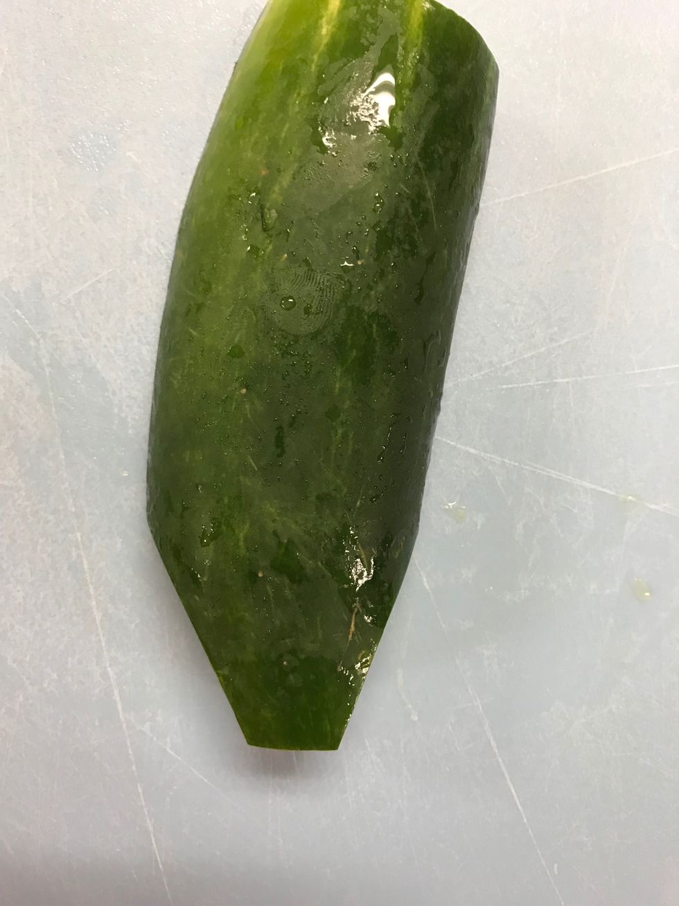 Slice off small right triangles at the bottom of the cucumber as pictured.