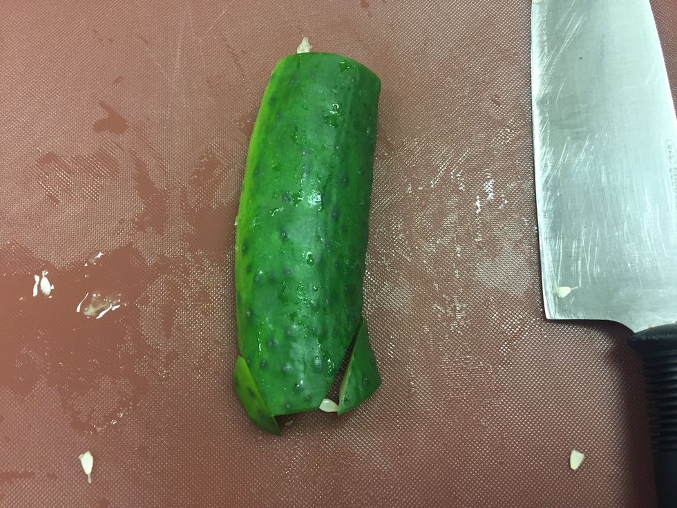 Slice off small right triangles at the bottom of the cucumber as pictured.